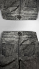 Gray denim jeans with a brand logo on the back pocket against a white background